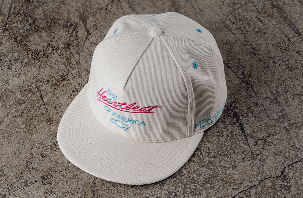 Lying on concrete is the Heat Wave Visual X Chevrolet Heart Beat of America Off-white hat.