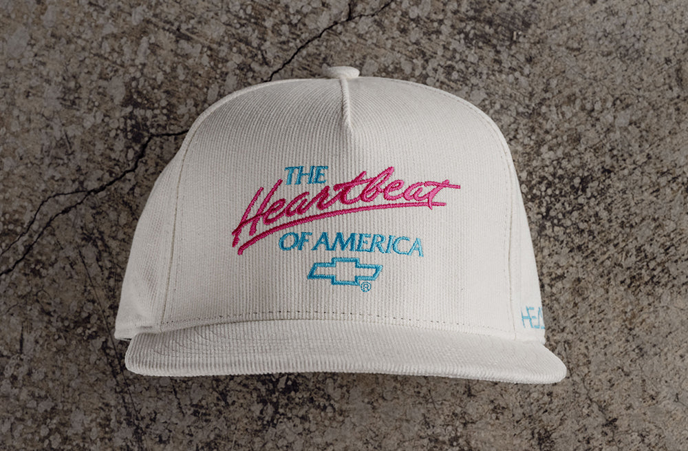 Lying on the ground is the Heat Wave Visual x Chevrolet Heart Beat of America Off-white Hat.