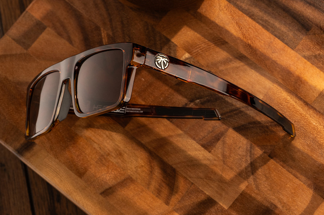 The Performance Rayth Sunglasses: Tortoise Z87+ with brown side shields lying on a wood table.