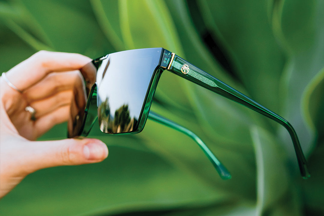 Hand holding the Clarity Sunglasses: Cycad Green