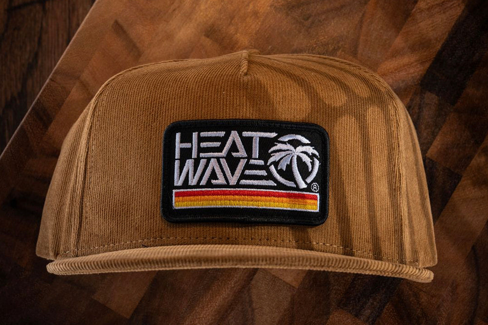 The Heat Wave Visual Retro Stripe Brown Hat on a wooden table.