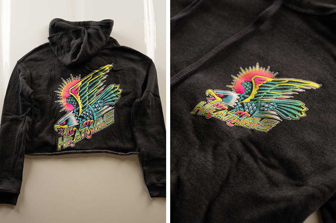Lying on the floor is the Heat Wave Visual Electric Eagle Ladies Crop Sweatshirt.