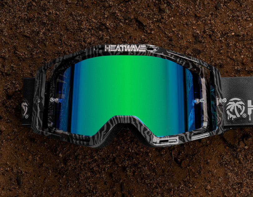 Lying on a dirt patch is the Heat Wave Visual MXG 250 Motosport Goggle in the Patrick Evans color way with a piff lens.