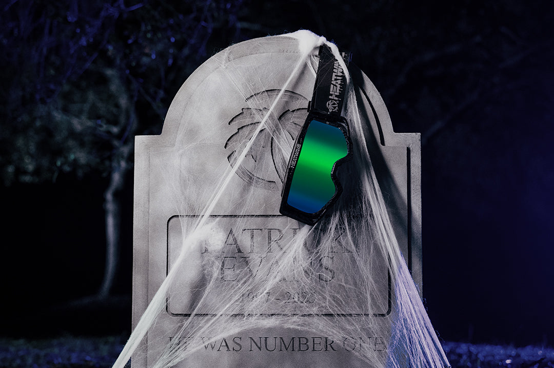 Heat Wave Visual MXG 250 Motosport Goggle in the Patrick Evans color way with a piff lens on a tombstone with spider webs at night.