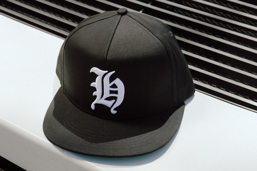 The Heat Wave Magnum Hat - Black placed on top of a car