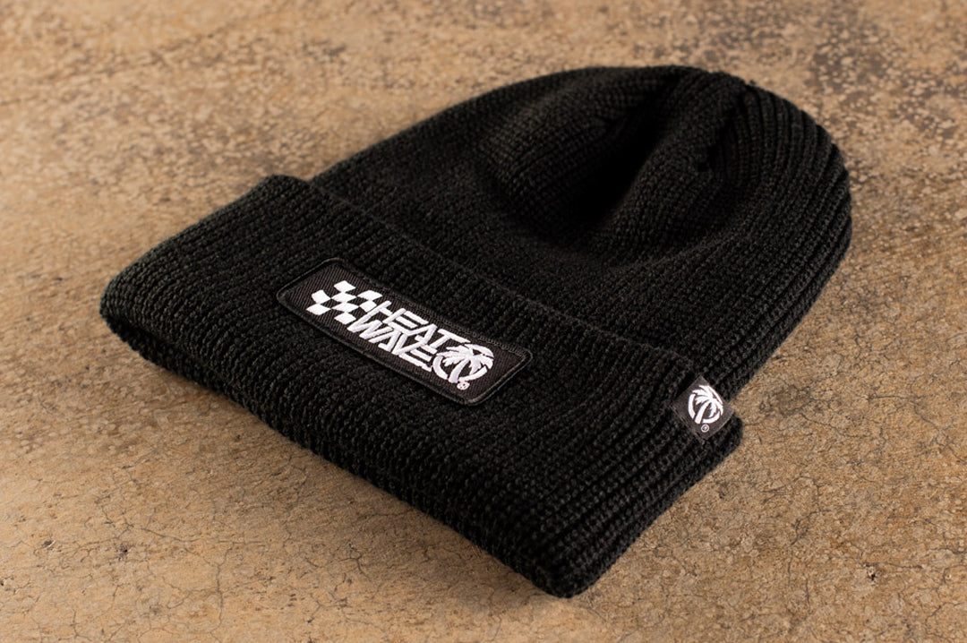 Close up on the knit tag on the Heat Wave Visual Racing Black Beanie.