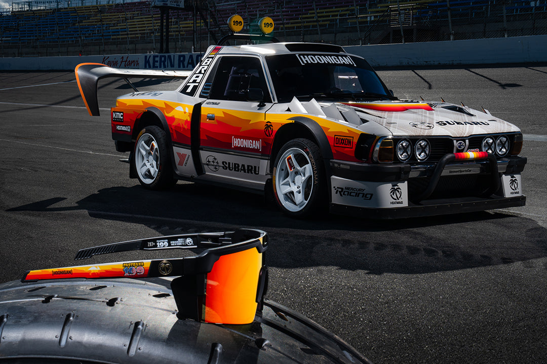 The Heat Wave Visual Future Tech Hoonigan Pastrana Sunglasses lying on tire in front of the Brataroo.