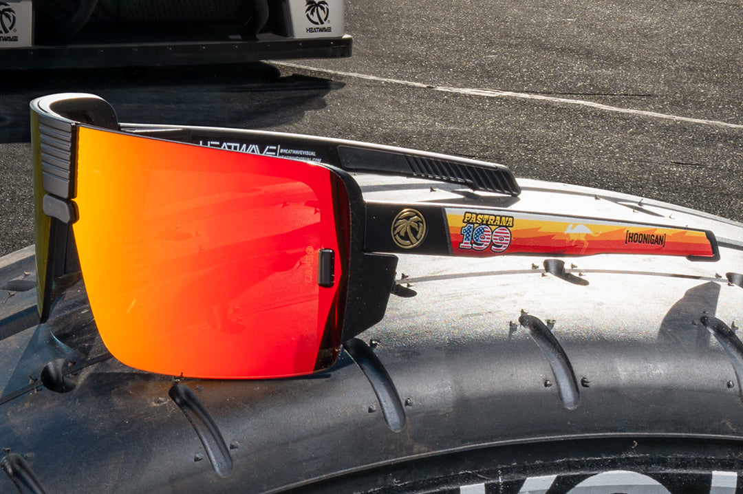 Lying on a a tire is the Heat Wave Visual Vector Hoonigan Pastrana Sunglasses. 