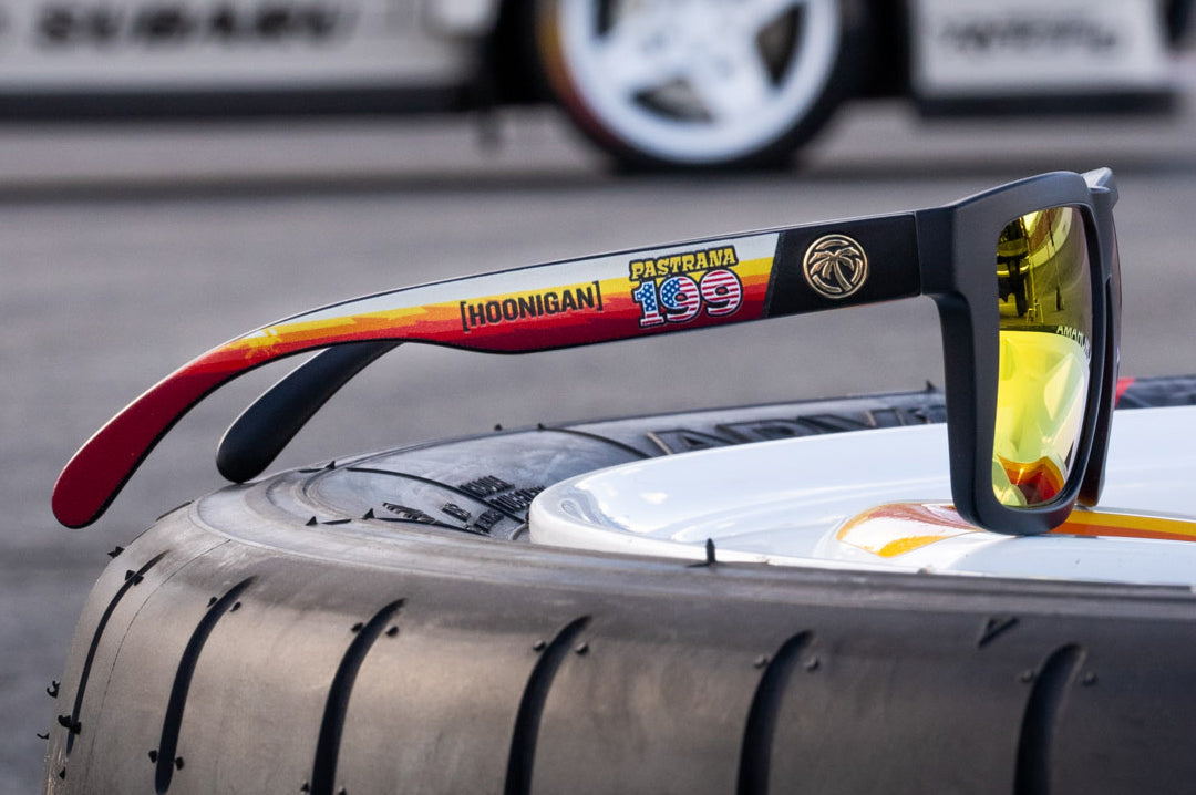 Lying on a tire is the Heat Wave Visual Vise Hoonigan Pastrana Sunglasses. 