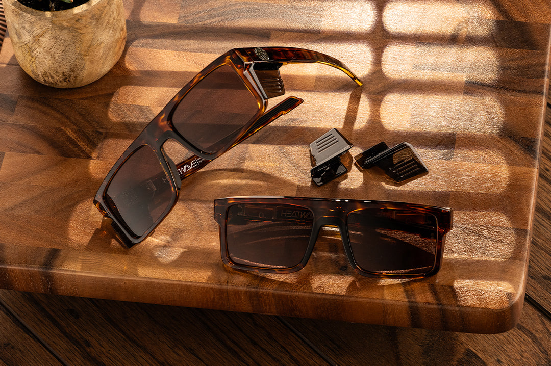 Two pairs of the Performance Rayth Sunglasses: Tortoise Z87+ with brown side shields lying on a wood table. 