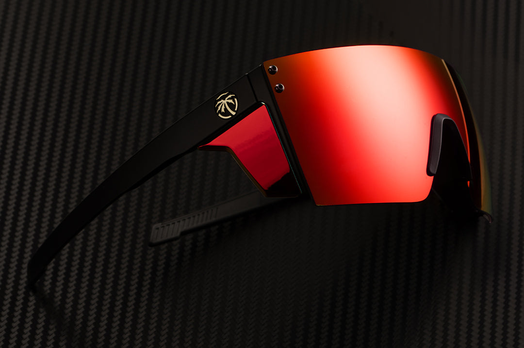 Laying on it's side is the Heat Wave Visual XL Lazer Face Sunglasses with black frame, red orange lens and matching colored side shields.