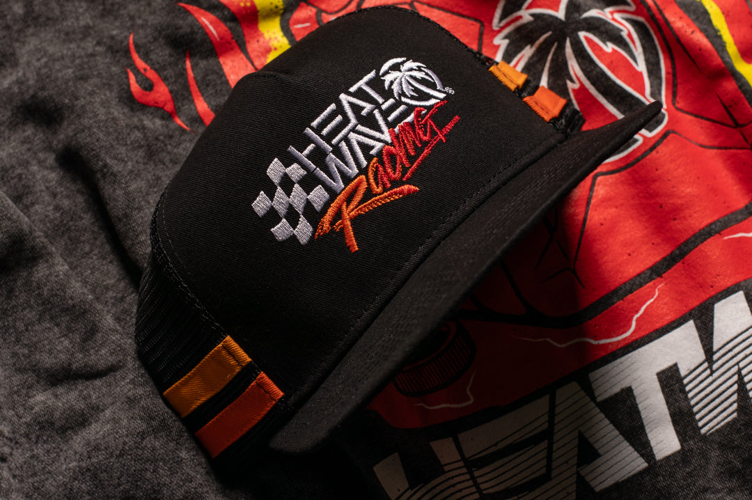 Laying on the sweatshirt is the Heat Wave Visual Racing Trucker Hat.