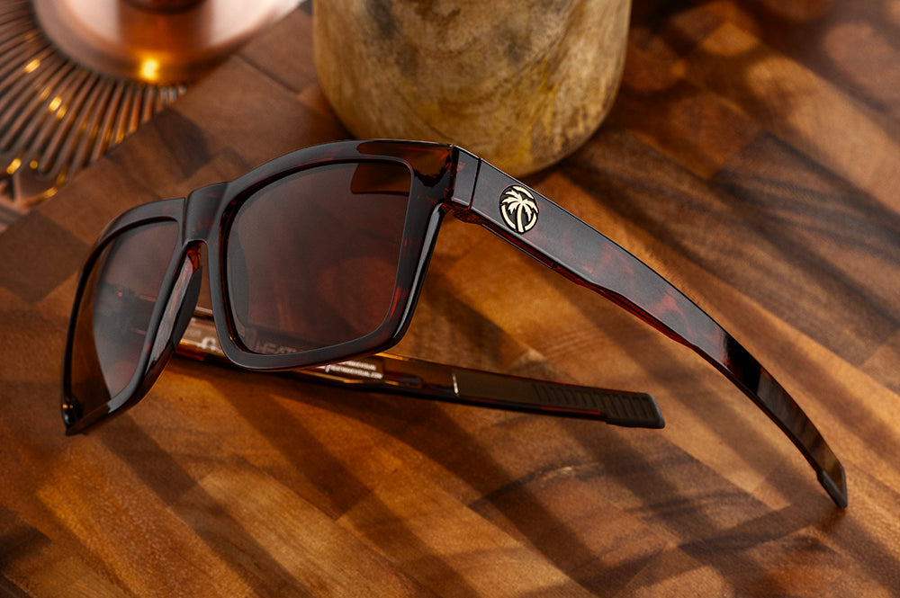 On a wooden table is the Heat Wave Visual Performance Vise Tortoise Sunglasses.
