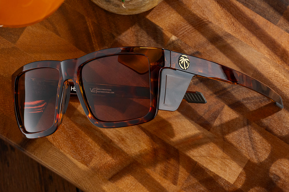 Lying on a wooden table is the Heat Wave Visual Performance XL Vise Tortoise Sunglasses. 